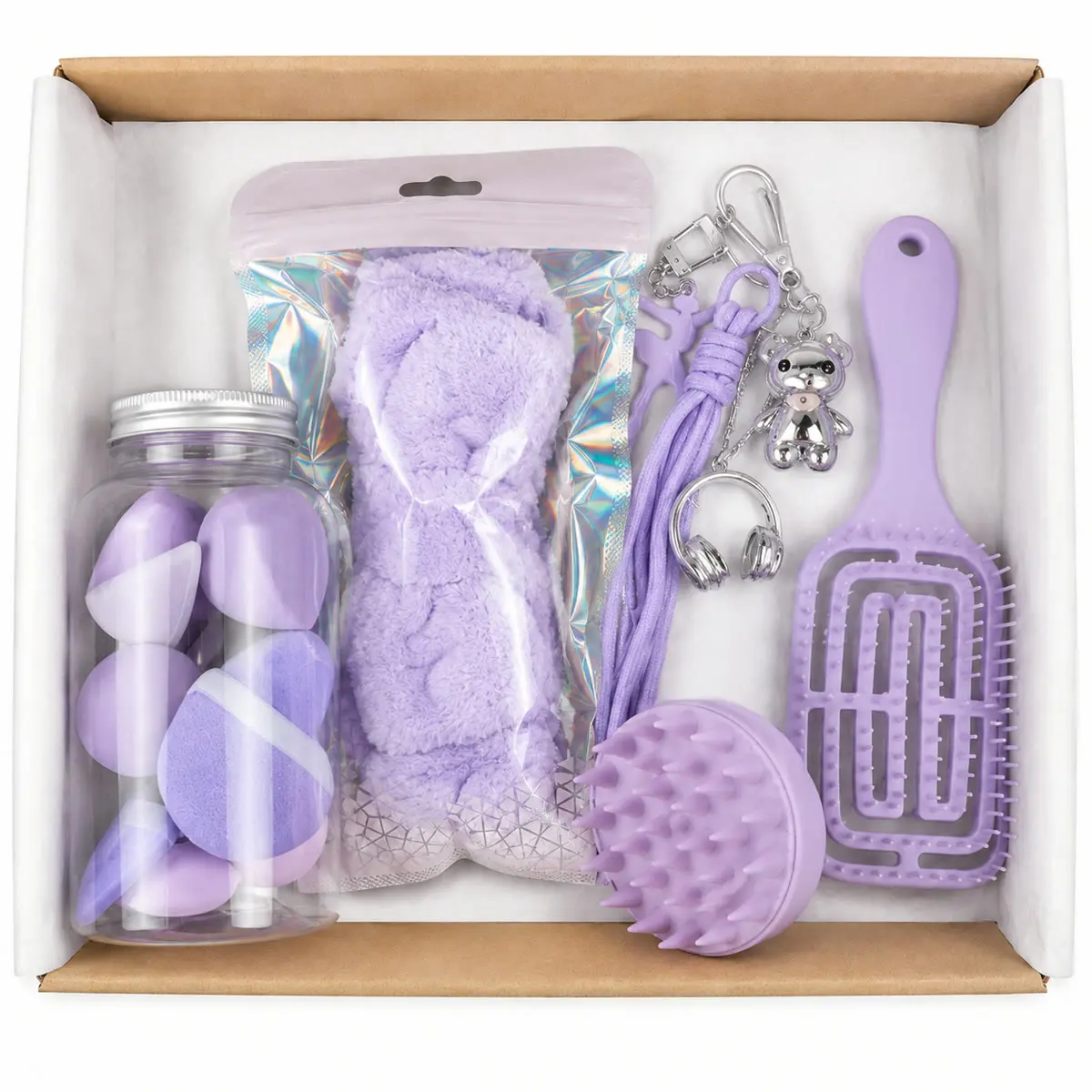 Caja abierta del combo de belleza con el frasco de esponjas, la vincha, los dos cepillos y el charm, todo en tono lila